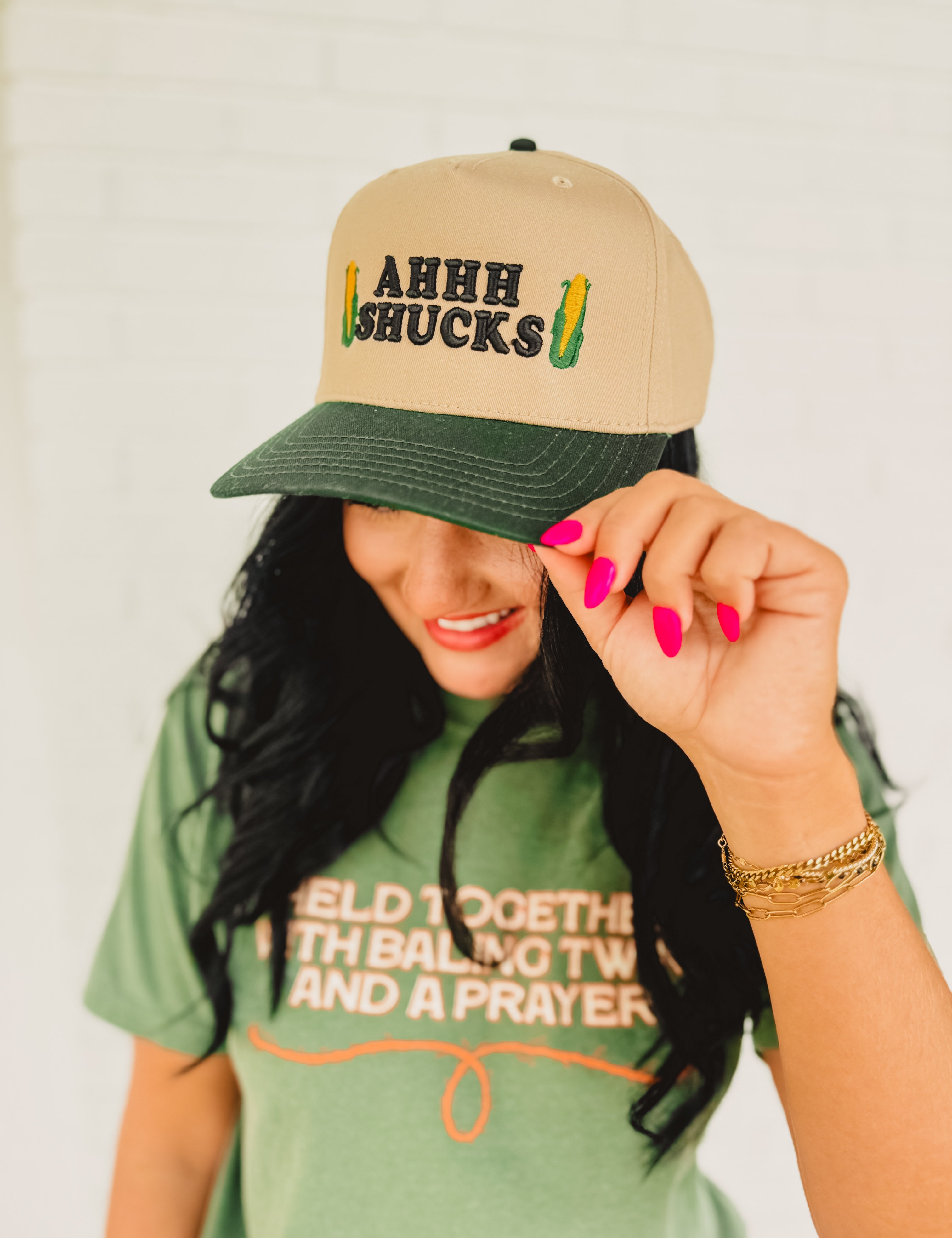 Two tone adjustable baseball cap with a cute corn pun that reads "Ahhh Shucks" featuring corn graphics.