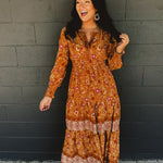 Border printed long sleeve maxi dress with a split neck and smocked waistband in the color pumpkin.
