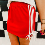 Red track mini skirt with white side stripes and bow details.