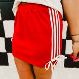 Red track mini skirt with white side stripes and bow details.