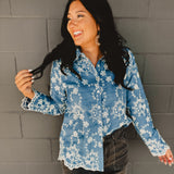 Blue denim flower embroidered long sleeve button down top with scalloped edge hemming and a collar.