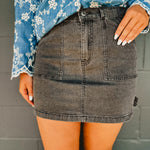 Washed black denim mini cargo skirt with pockets and stretch.