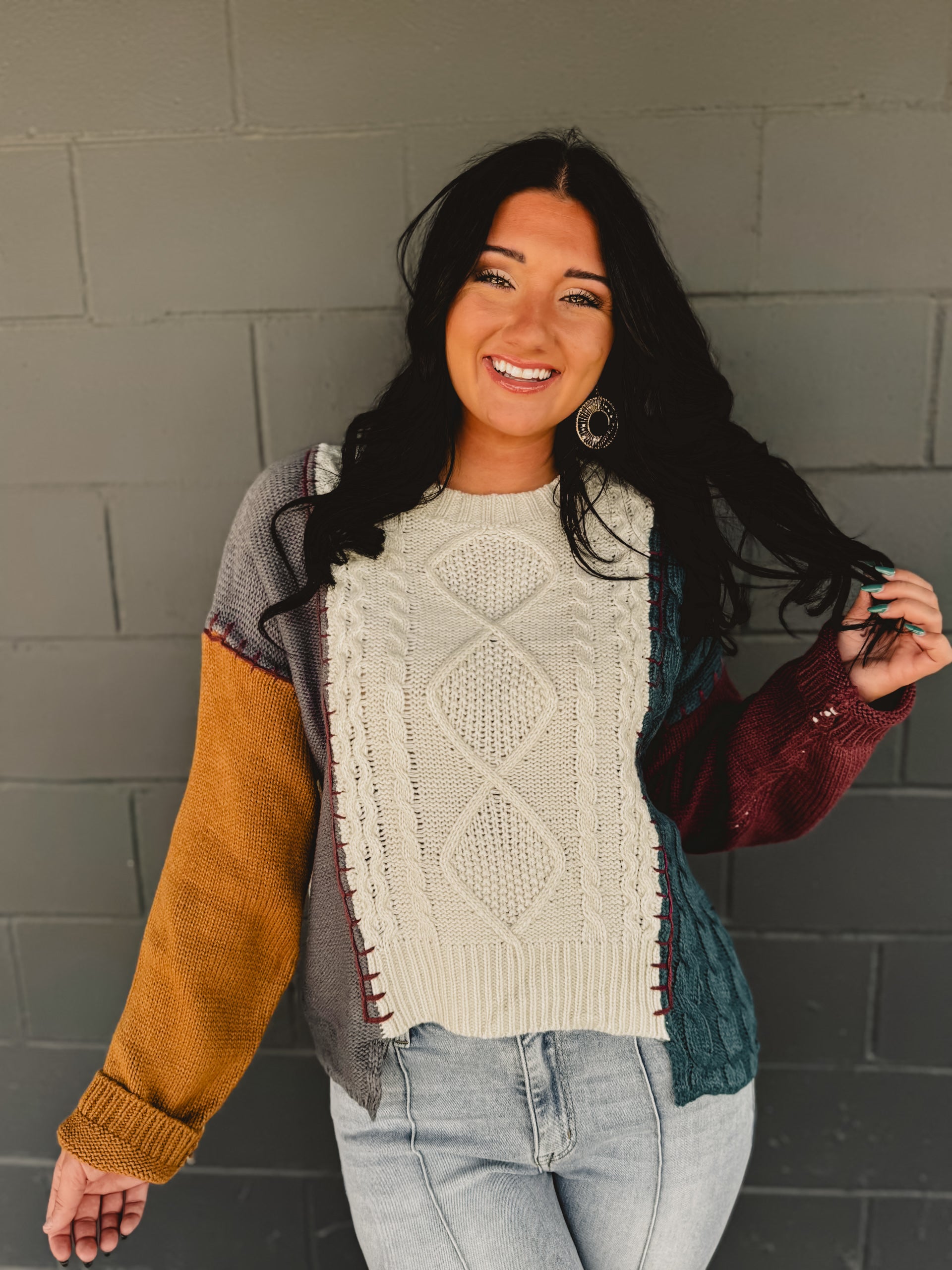 Color block cable knit sweater with exposed stitching in beige multi.
