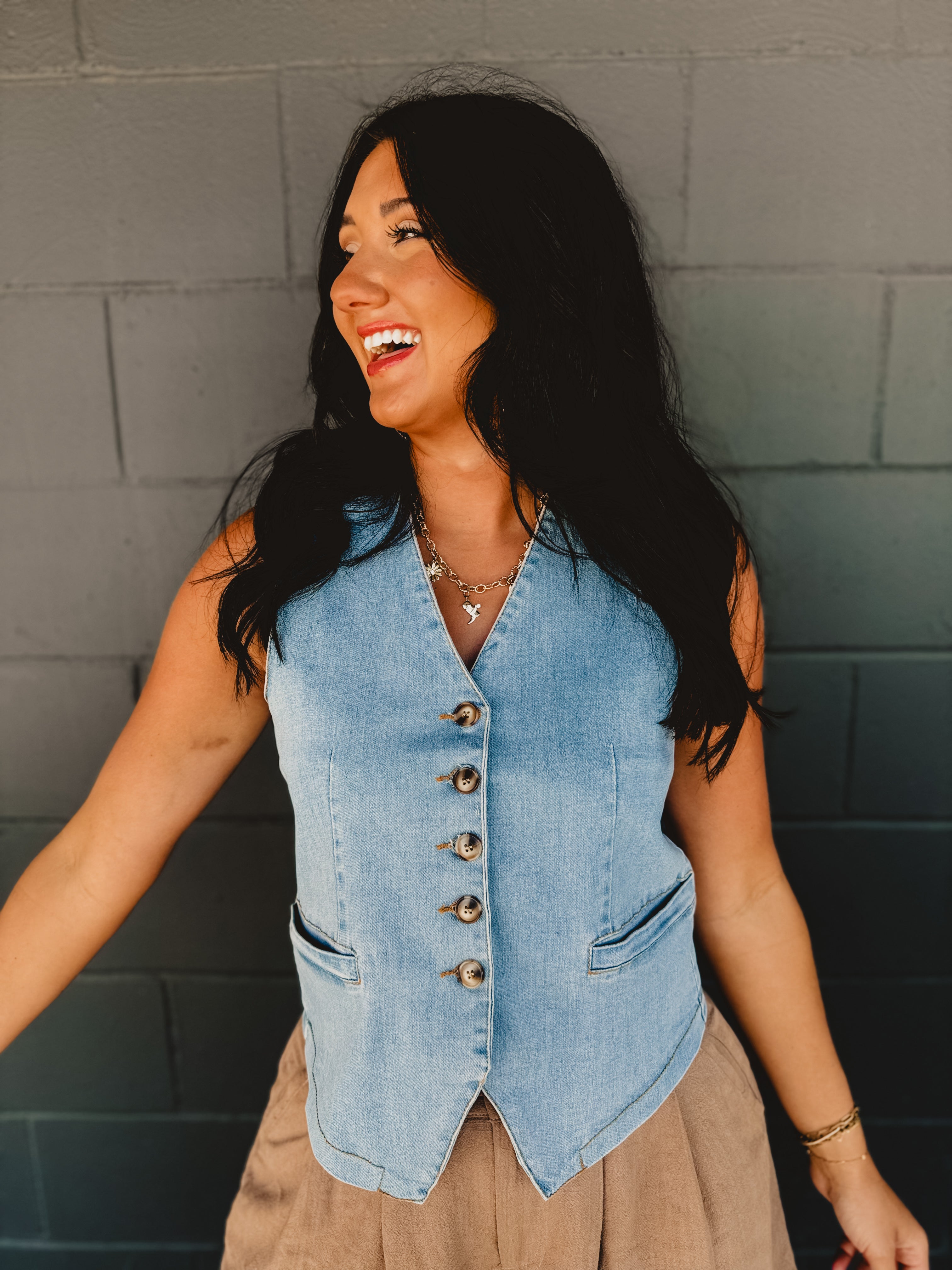 V-neck light wash denim button up sleeveless vest with front pockets.