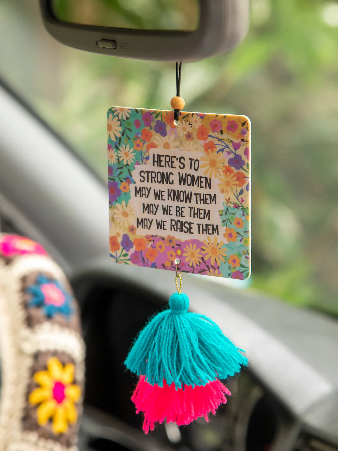 Natural Life car air freshener in voilet-scented essential oil freshie that reads "Here's to strong women. May we know them, may we be them, may we raise them."