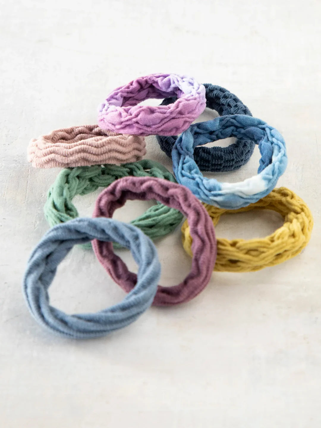 Set of 8 stretchy Natural Life hair ties with various textures and colors.