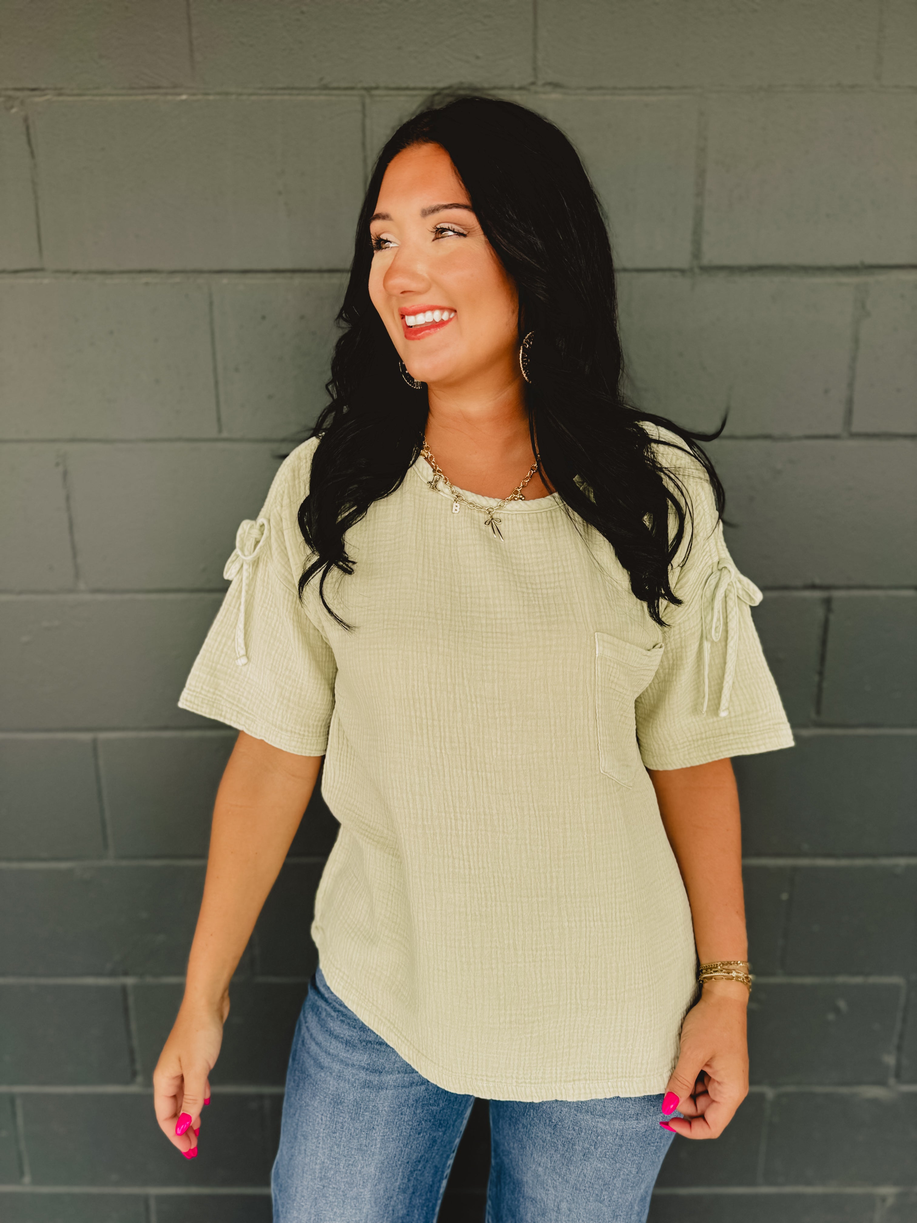 Gauze material oversized short sleeve top with ruched shoulders and bow ties in the color light sage.
