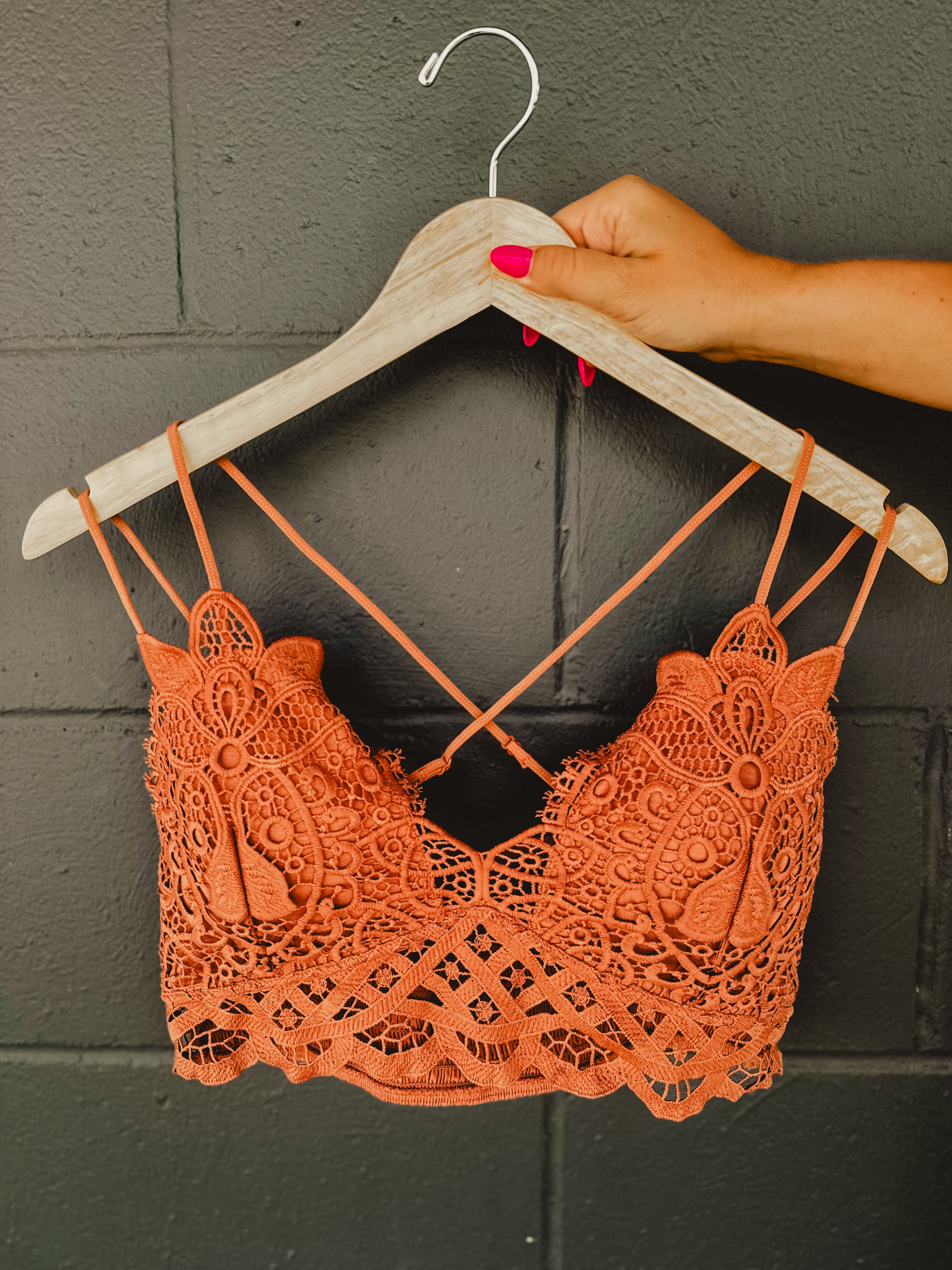 Terracotta colored lace crochet bralette with a scalloped edge and two straps on each side.