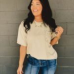 Short sleeved oversized top with drop shoulders, a front crochet pocket, and side slits in khaki.