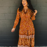 Border printed long sleeve maxi dress with a split neck and smocked waistband in the color pumpkin.