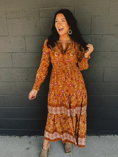 Border printed long sleeve maxi dress with a split neck and smocked waistband in the color pumpkin.