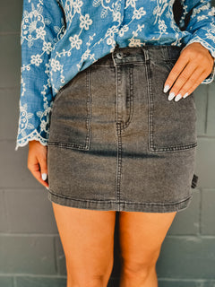 Washed black denim mini cargo skirt with pockets and stretch.