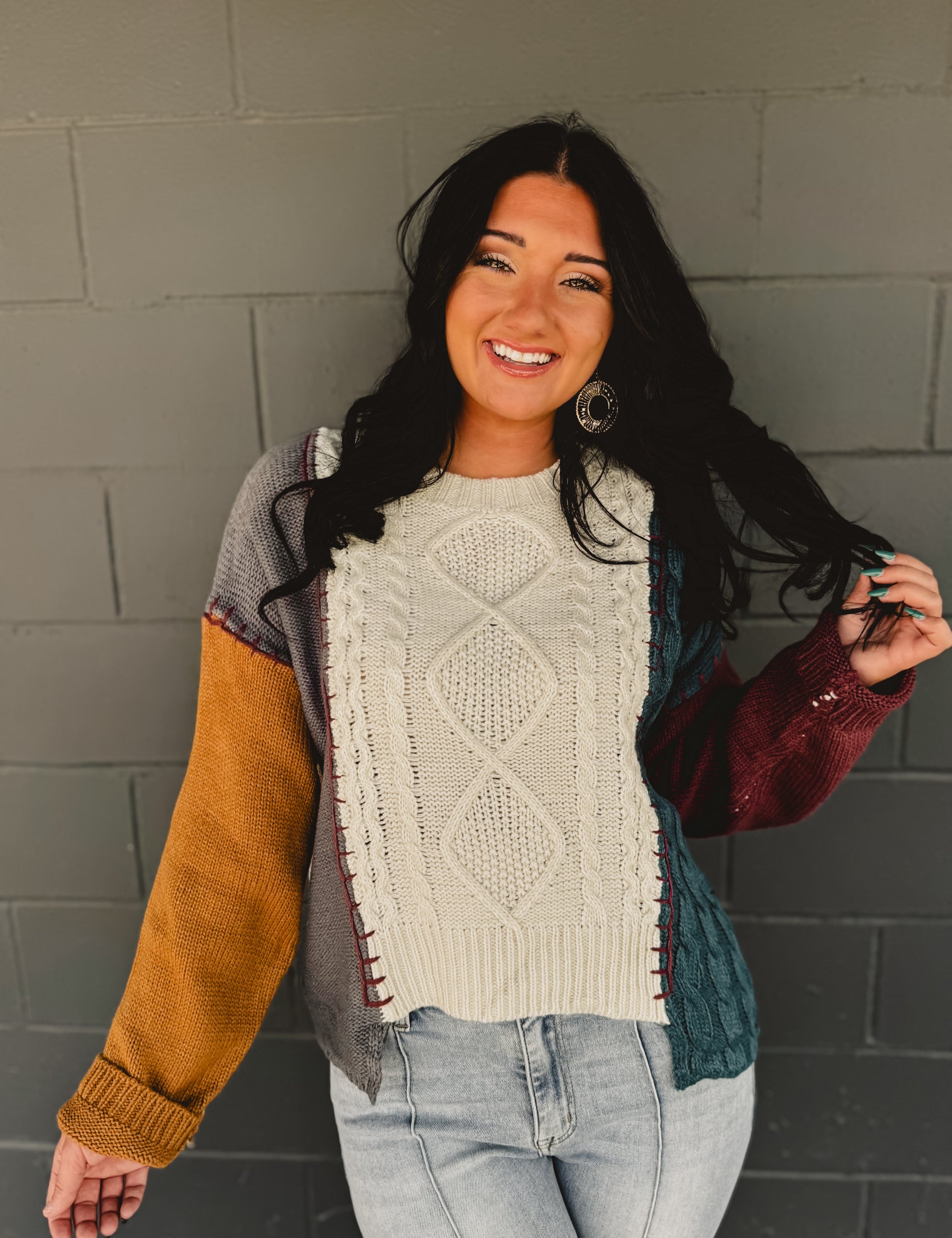 Color block cable knit sweater with exposed stitching in beige multi.