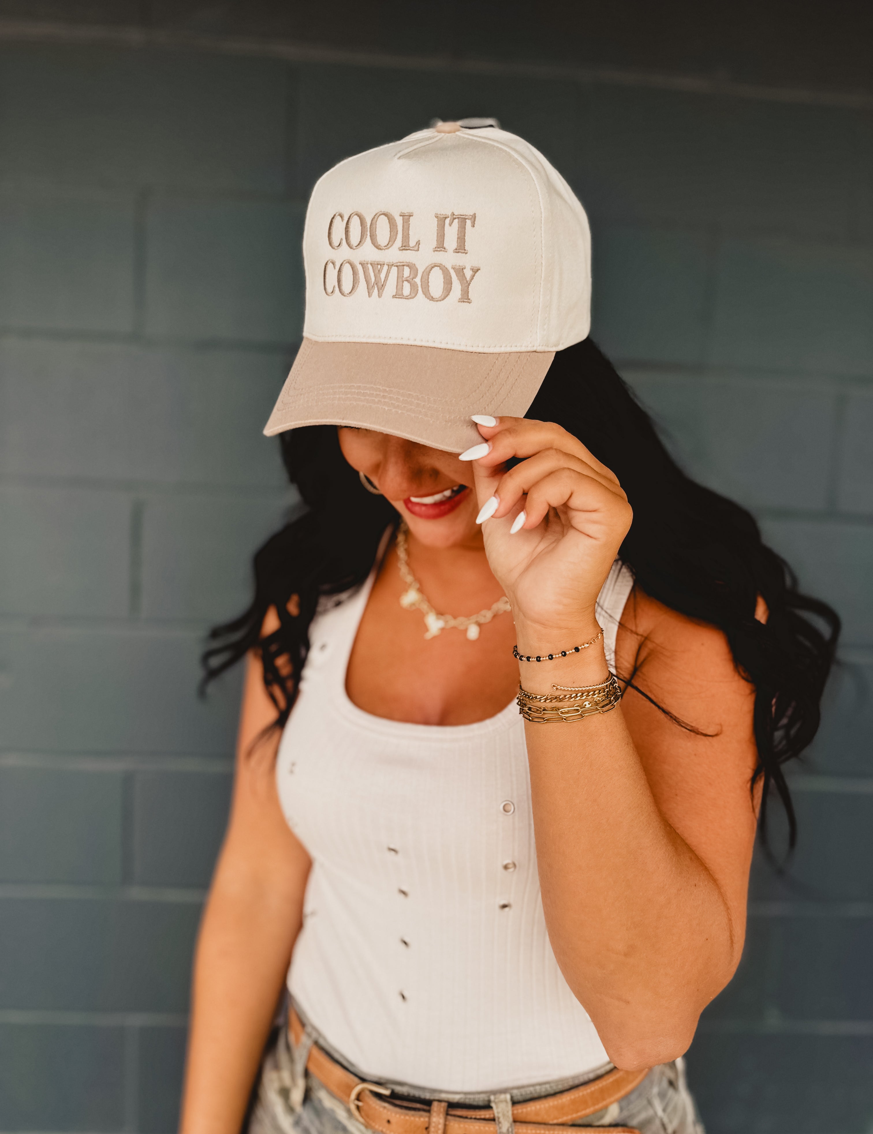 Two-toned one size baseball cap reading "Cool It Cowboy" in a cream and beige color.