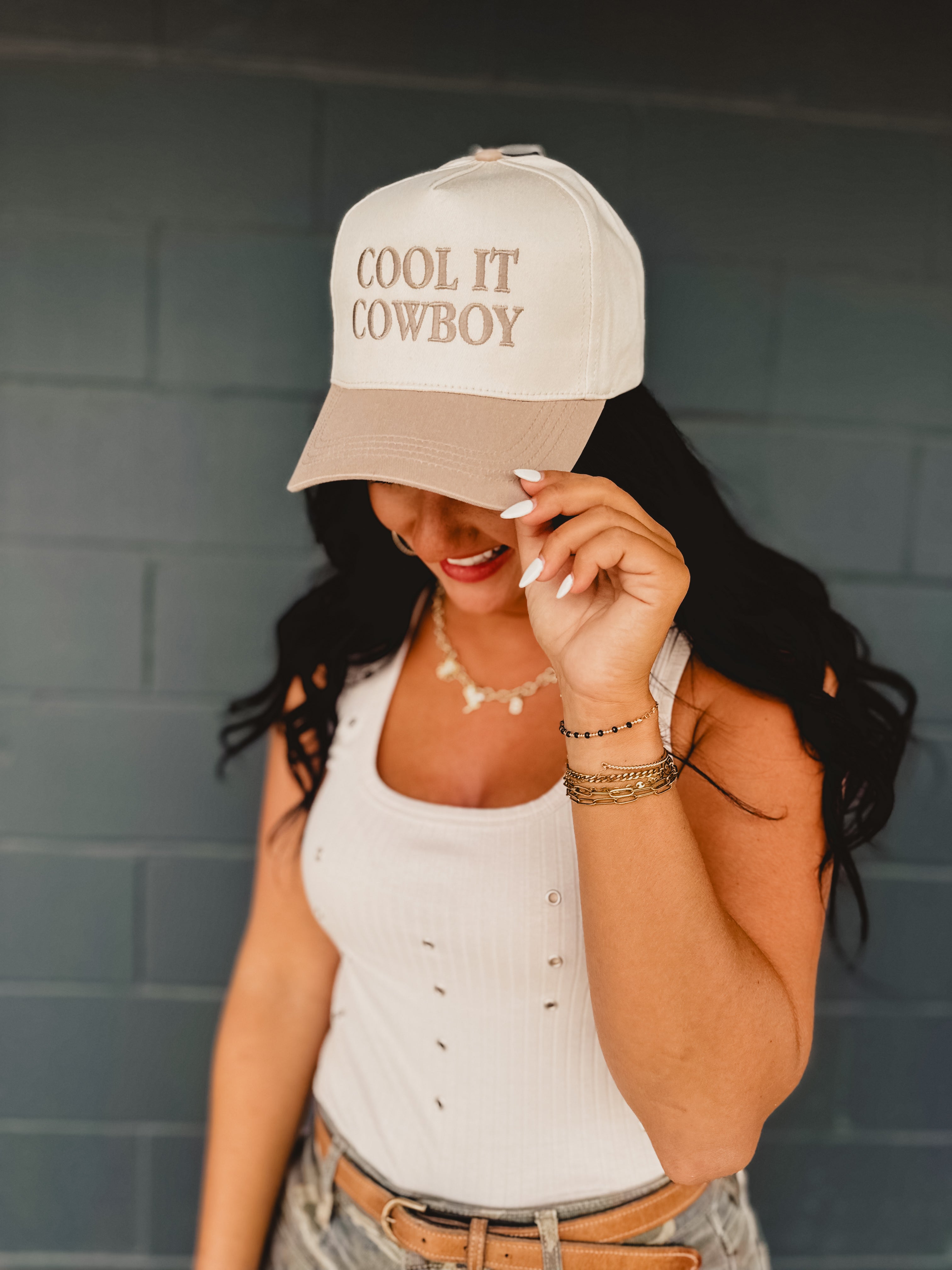 Two-toned one size baseball cap reading "Cool It Cowboy" in a cream and beige color.