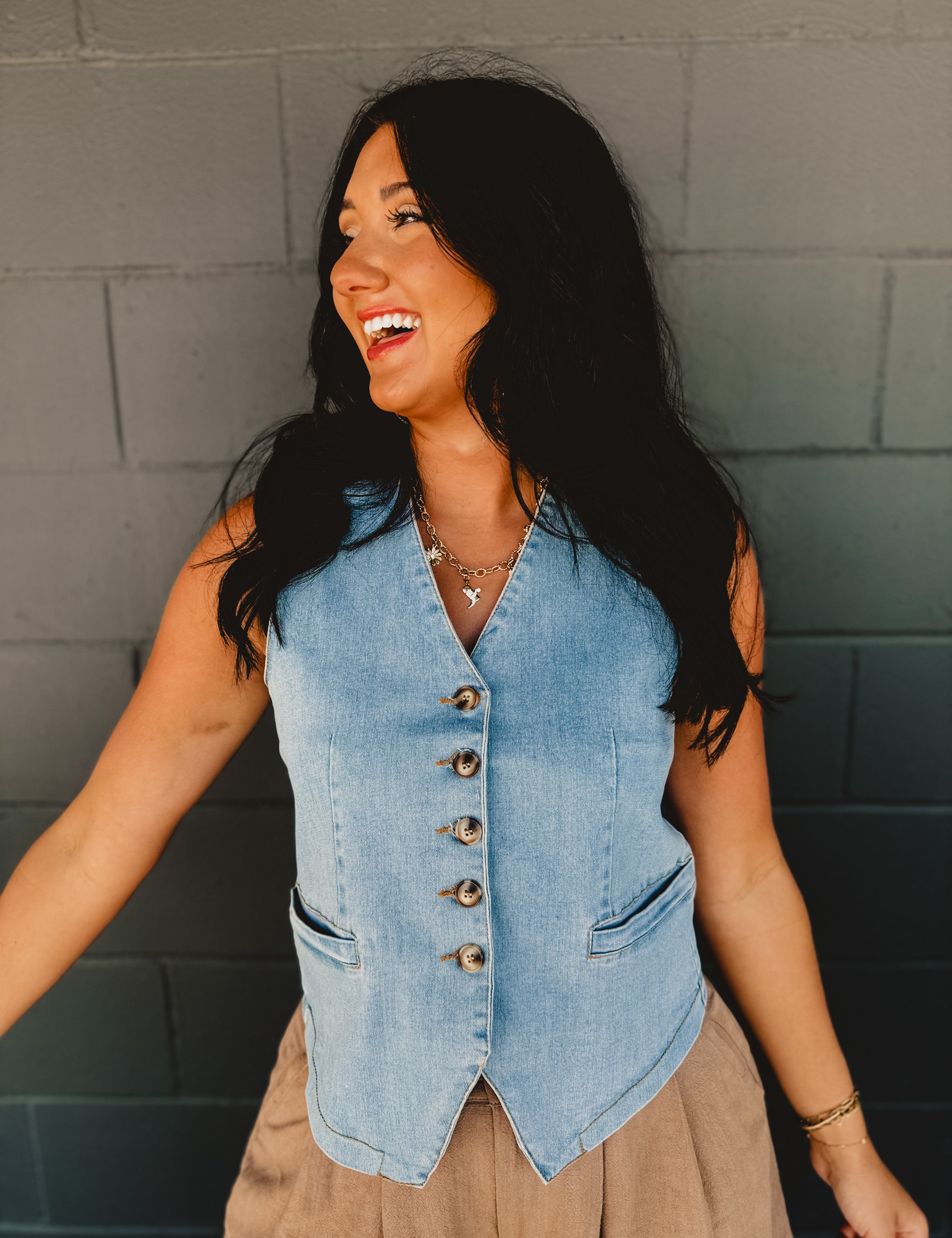 V-neck light wash denim button up sleeveless vest with front pockets.