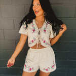 Short sleeved tie-up cropped blouse with floral embroidery and scalloped crochet details.
