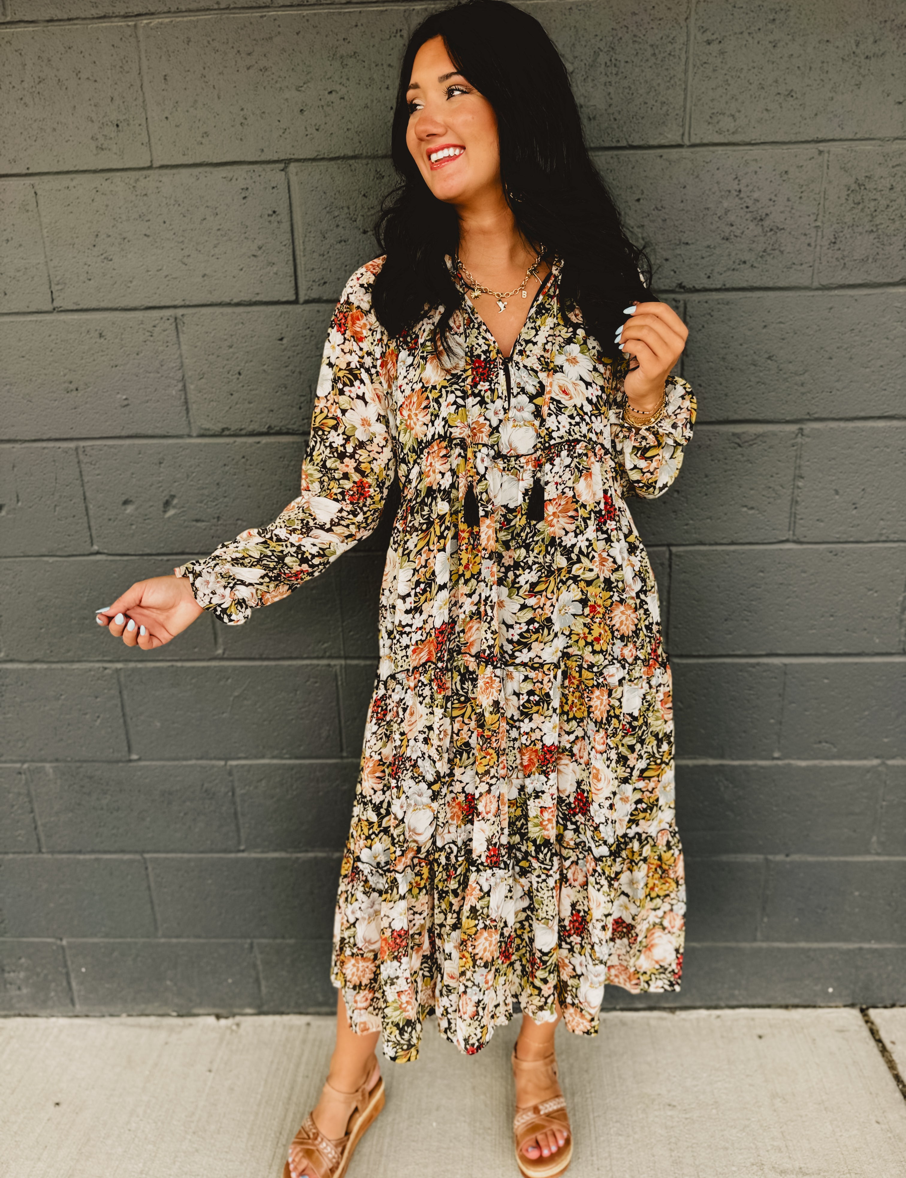 Long sleeve deep v-neck floral tiered midi dress with ruffle hems and tassels in black.