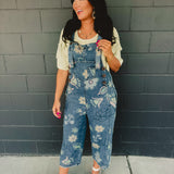 Floral printed denim cropped overalls with front pockets and chunky buttons.
