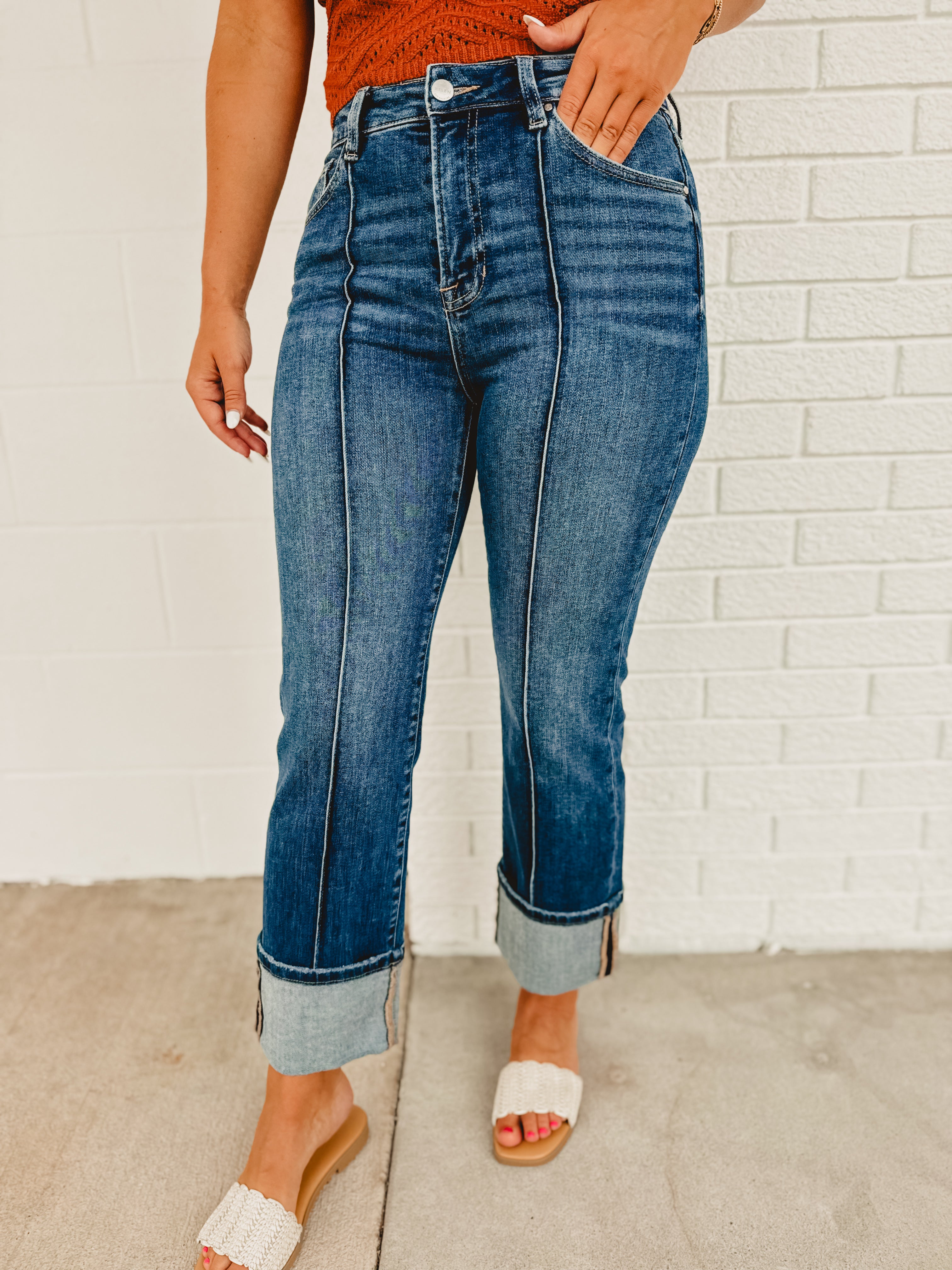 High rise-ankle wide cuffed zip-up dark denim jeans with front seam and back and front pockets.