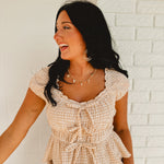 Sweetheart neckline short sleeved gingham print blouse with tie details and ruffled hems.