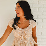 Sweetheart neckline short sleeved gingham print blouse with tie details and ruffled hems.