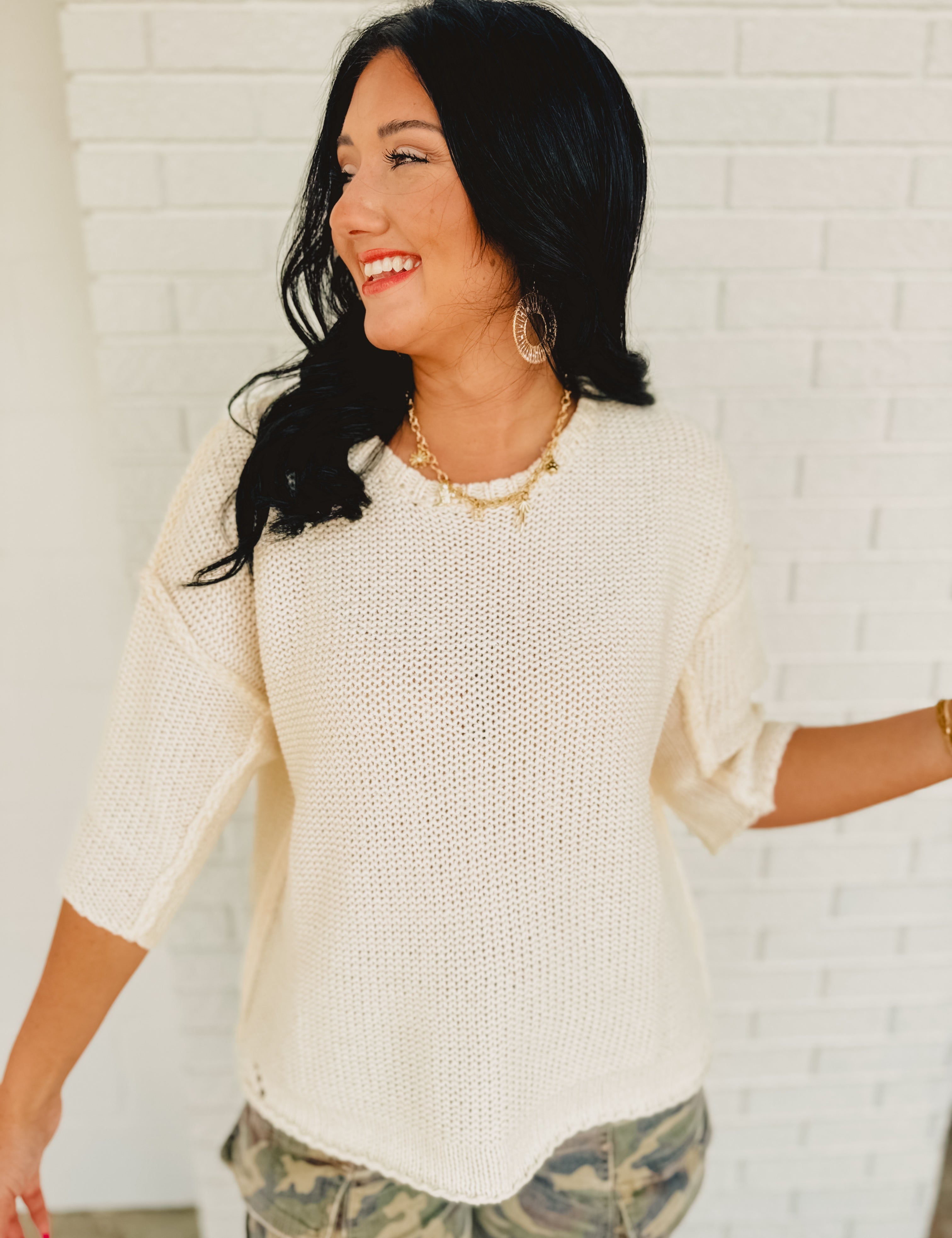 Cream colored half sleeve knit sweater with a rounded neckline and drop shoulders.