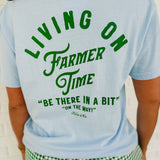 Light blue "Living On Farmer Time" short sleeved graphic tee with a round neck and green writing.