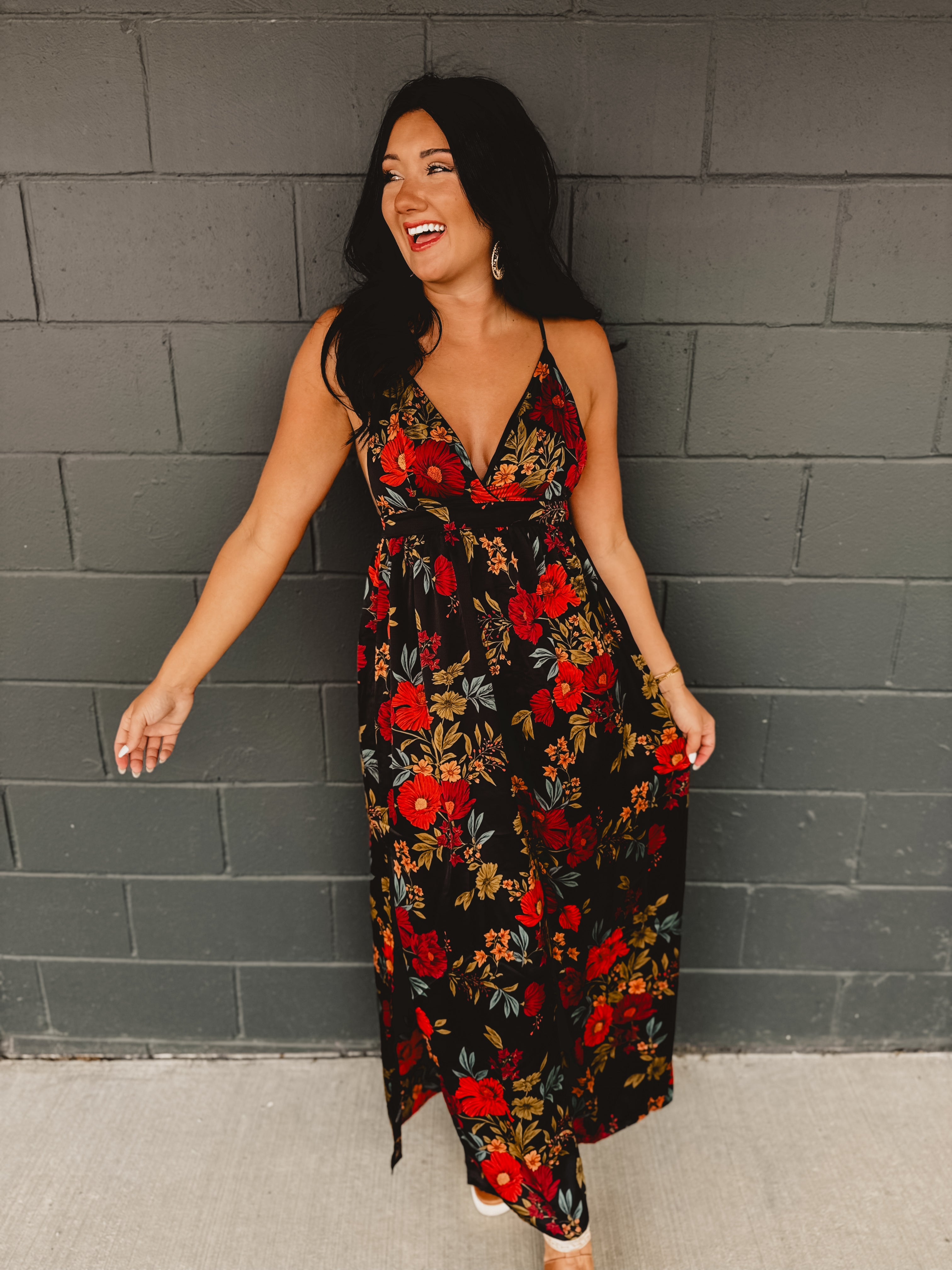 Black satin maxi dress with an empire waist and A-line skirt, featuring adjustable criss-cross back straps, a plunging neckline, and an open-back silhouette.