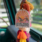 Natural life strawberry-scented essential oil car air freshener that reads "Stop. Smile. Breathe. Life Is Beautiful." It features double-sided artwork with sunset and scenery graphics and hanging tassels.