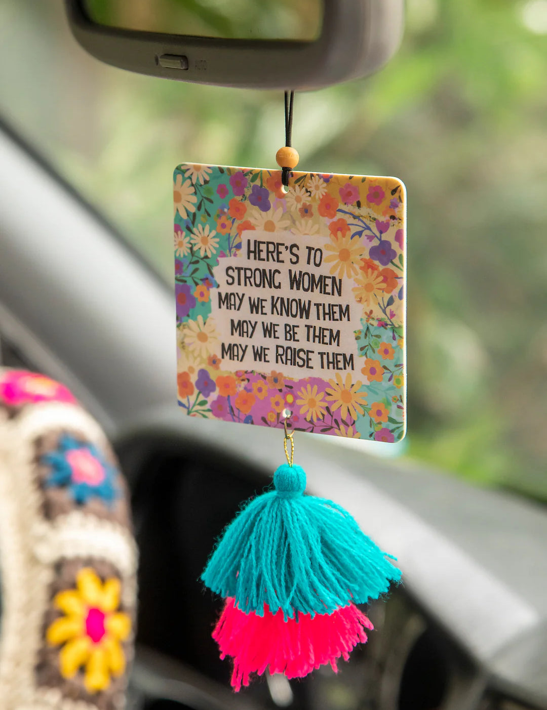 Natural Life car air freshener in voilet-scented essential oil freshie that reads "Here's to strong women. May we know them, may we be them, may we raise them."