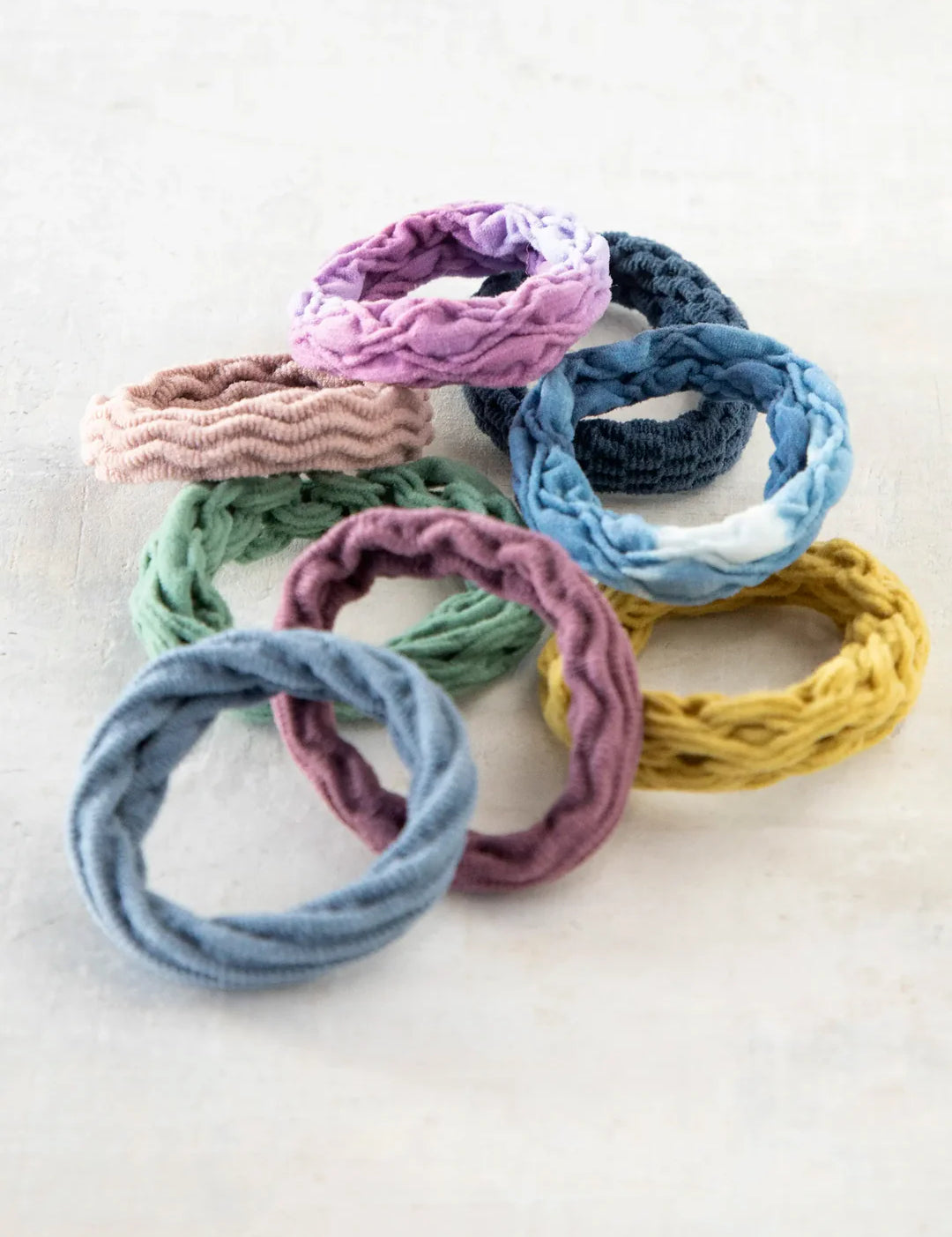 Set of 8 stretchy Natural Life hair ties with various textures and colors.