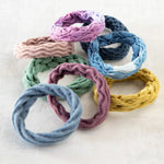Set of 8 stretchy Natural Life hair ties with various textures and colors.