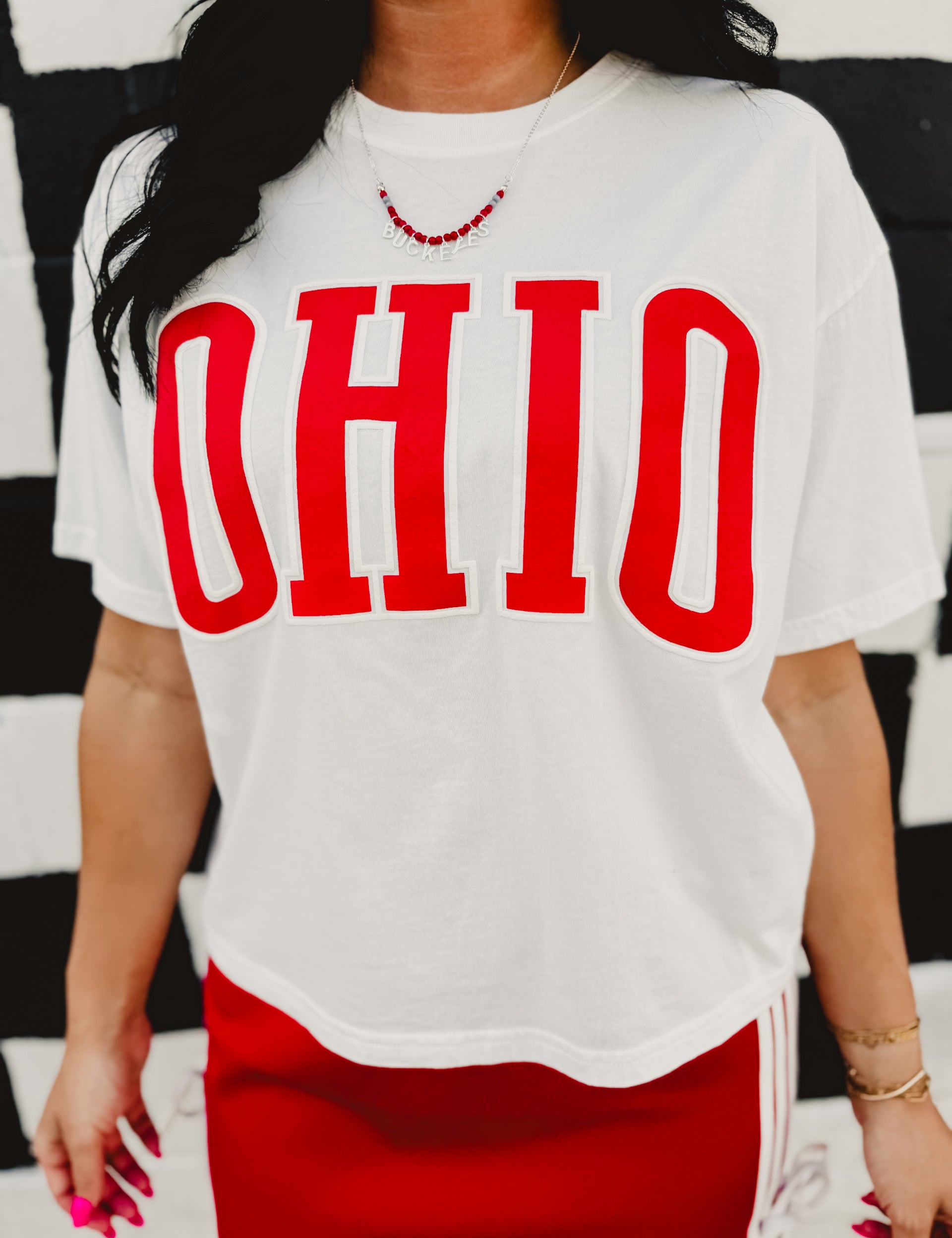 Cropped "Ohio" varsity letter white short sleeved graphic tee with a round neckline.