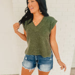 V-neck sleeveless green sweater vest with side slits.