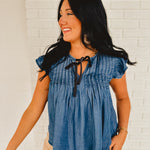 Denim pleated top with tie-up black bow detail and ruffle short sleeves.