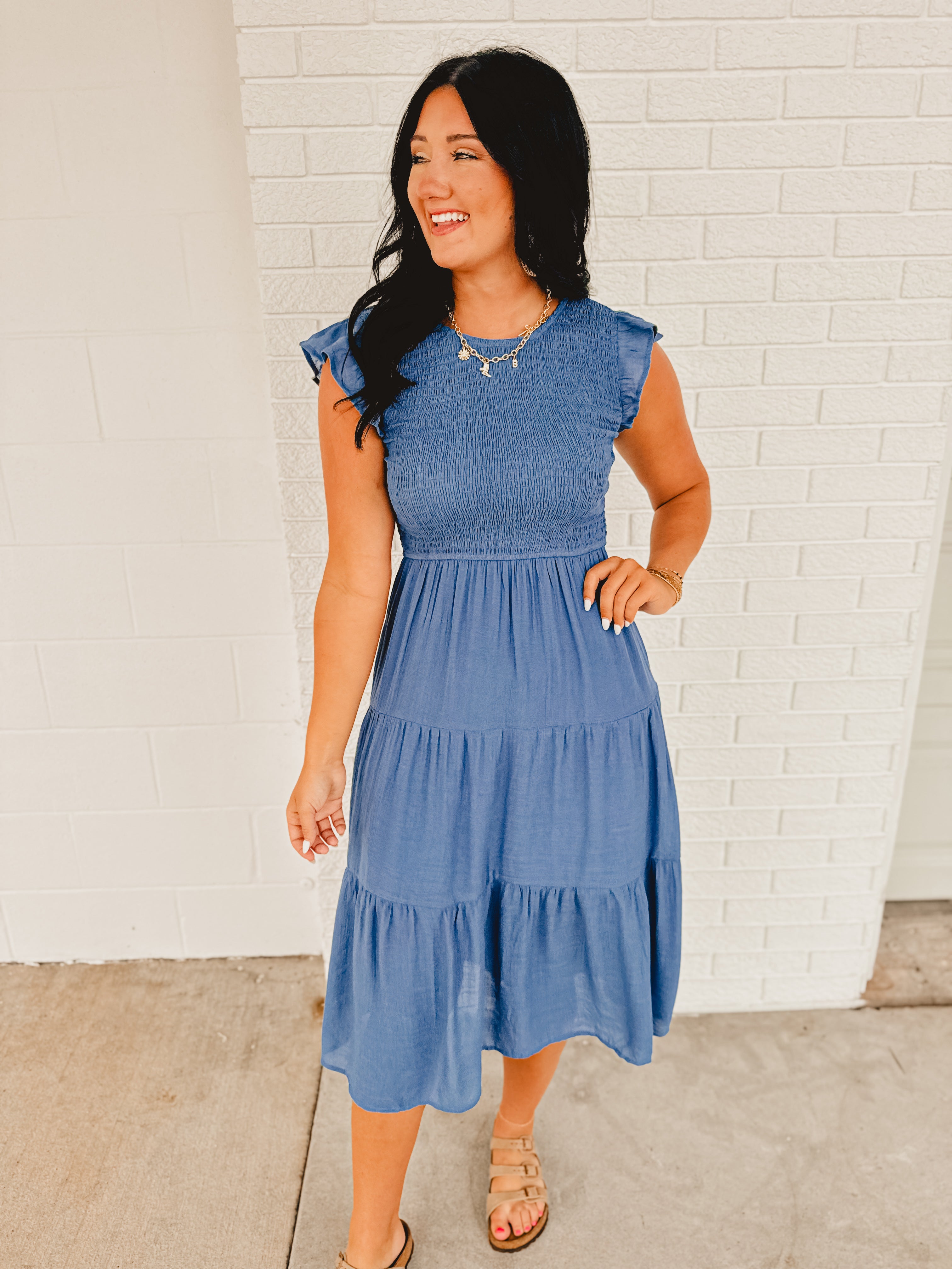 Midi dusty blue tiered and smocked dress with ruffle sleeves and a rounded neck.