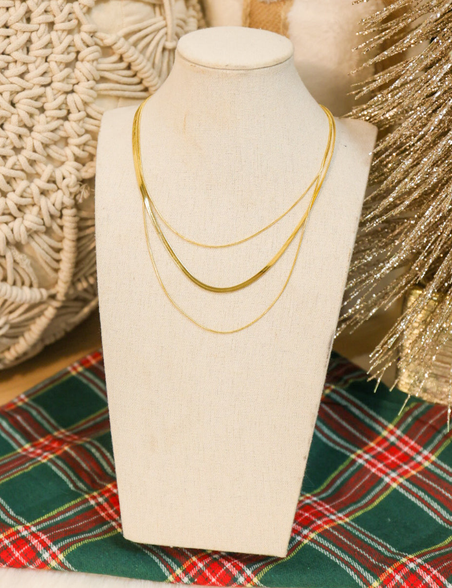 Triple layered snake and herringbone chain link necklace in gold.