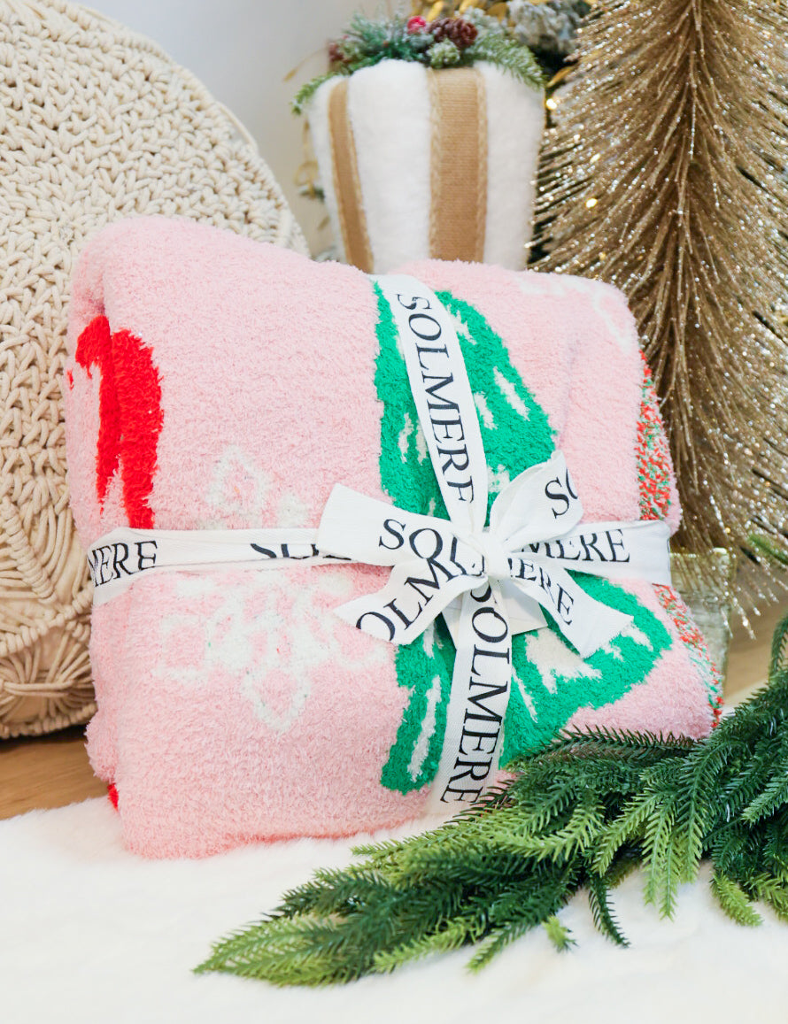 Super soft Christmas tree, bows, and snowflake decorated blanket in pink.