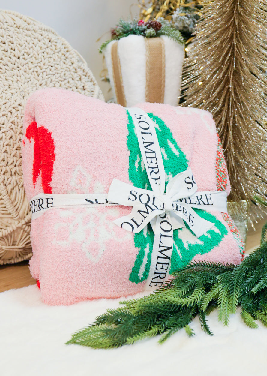 Super soft Christmas tree, bows, and snowflake decorated blanket in pink.